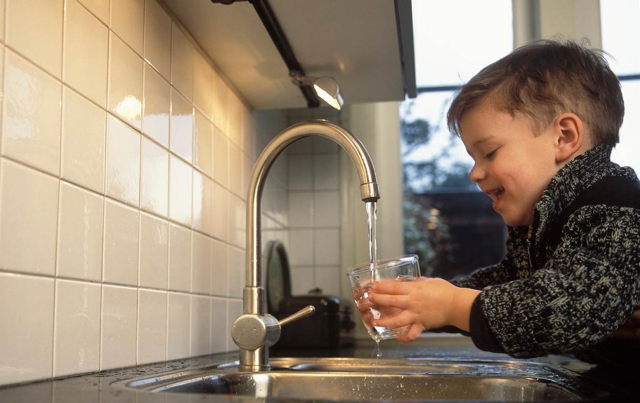 Een kindje vult een glas met water onder de kraan