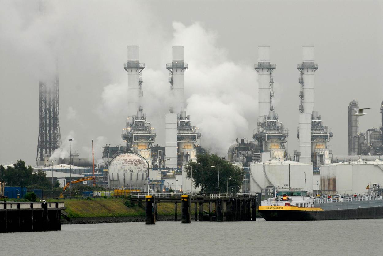 Een fabriek met rokende schoorstenen langs een kanaal