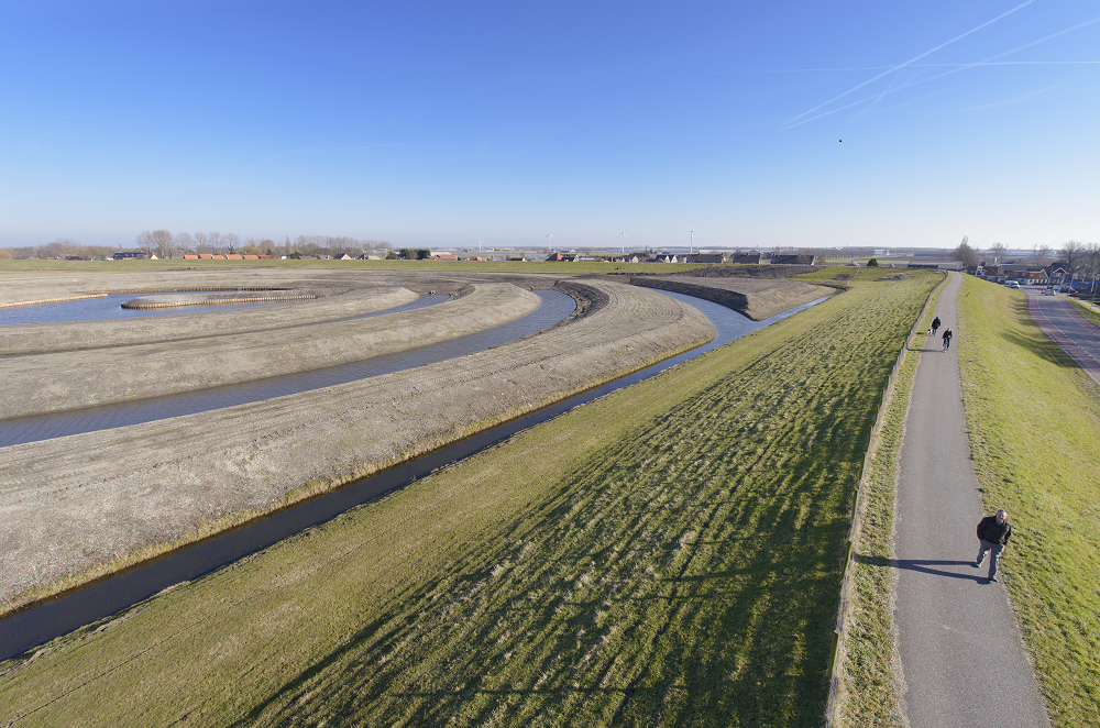 Een weg loopt over een dijkje langs een waterzuiveringsgebied