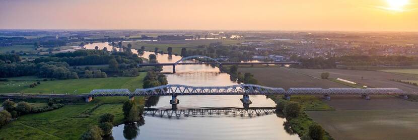 Luchtfoto van bruggen over de Maas bij zonsondergang