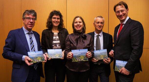 Vijf mensen staan op de foto met het boekje 'Watermanagement'. Minister Cora van Nieuwenhuizen staat in het midden.
