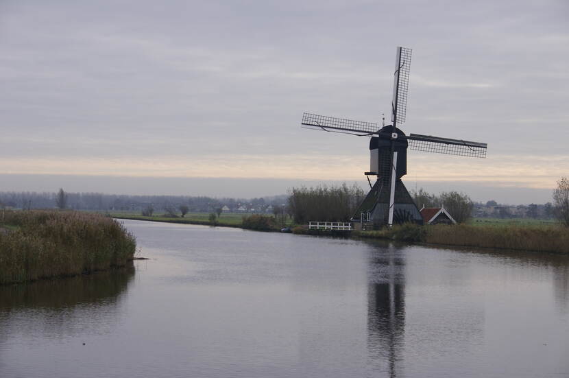 Een molen staat langs een kanaal.