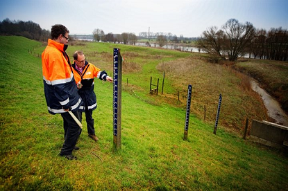 Dijkwachten bekijken waterpijl bij de dijk