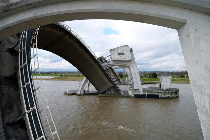 De stuw in de Rijn bij Amerongen, Maurik, de stuw staat open bij hoge waterstand, een schip vaart erdoorheen.