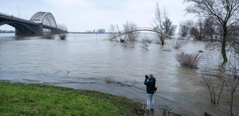 Man fotografeert rivier de Waal bij hoogwater