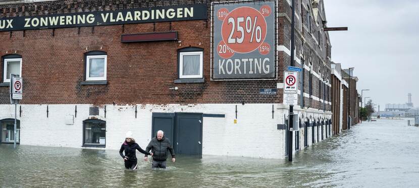 Mensen lopen huis uit tijdens hoogwater, straat onder water