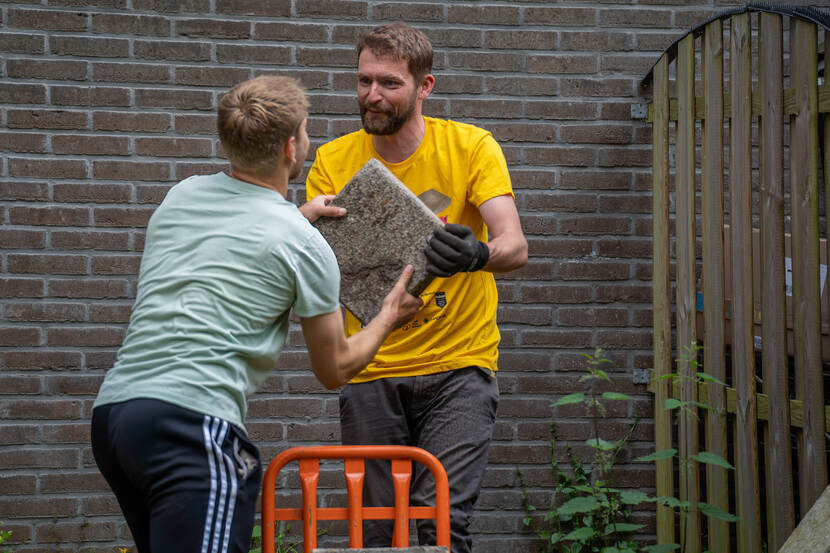 man geeft tegel aan andere man