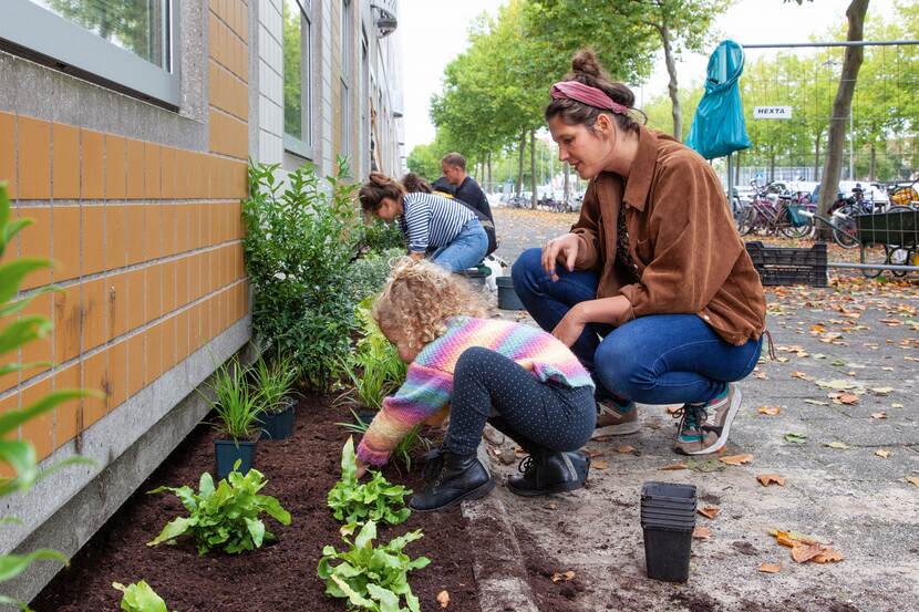 vrouw en kind werken aan geveltuin