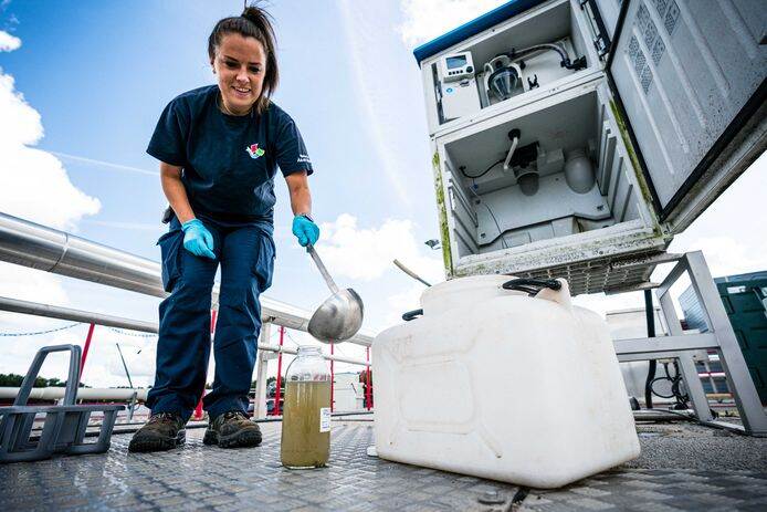 Een vrouw giet met een pollepel bruin water in een glazen pot.