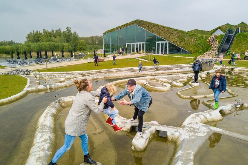 Bezoekers van het Biesbosch Museum Eiland lopen buiten over een labyrint met water daartussen