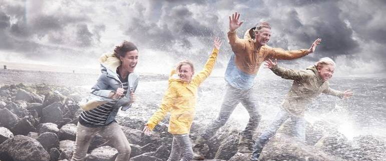 kinderen en vader lopen op dijk tegen wind in