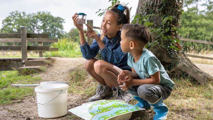 kinderen met waterdiertjes die zij gevangen hebben