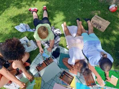 kinderen kleuren op kleed in het gras