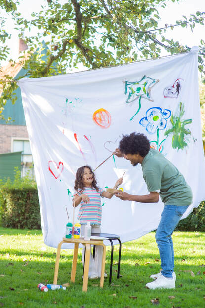 kind schildert met man op doek buiten
