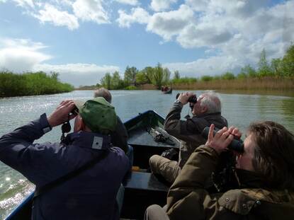 mensen kijken door verrekijker op boot